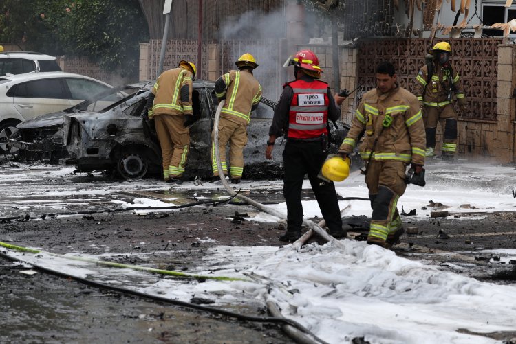 Image of firefighters standing near burned car