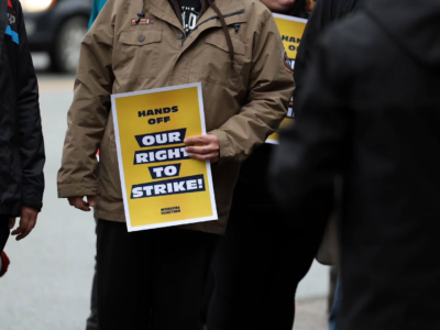 Person holding a Workers Together rally sign that reads, "Hands off our right to strike"